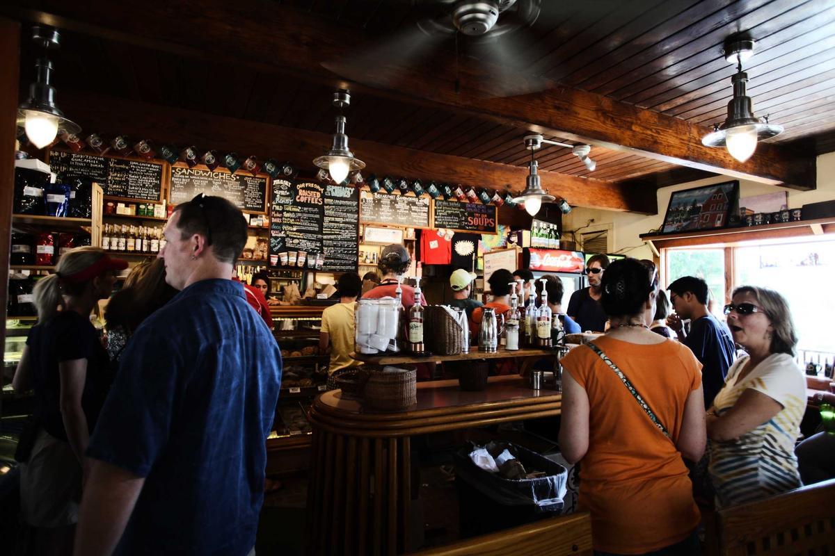 Clienți stând de vorbă la tejgheaua unei cafenele aglomerate